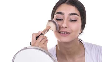 femme de race mixte se maquiller le visage avec un pinceau de maquillage photo