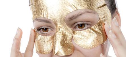 procédure cosmétique, le visage de la femme avec masque d'or sur fond blanc photo