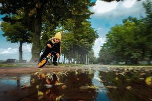 mignonne petite fille se promène dans les flaques d'eau à vélo au parc photo