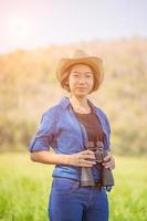 femme porter un chapeau et tenir des jumelles dans un champ d'herbe photo