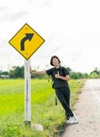 femme debout avec sac à dos faisant de l'auto-stop le long d'une route photo