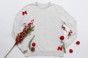 gros plan sweat-shirt modèle vierge blanc avec espace de copie et concept de vacances de noël. sweat à capuche maquette vue de dessus et décorations de vacances rouges sur fond blanc. accessoires de bonne année. tenue de noël photo