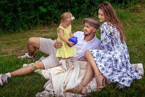 parents avec leur fille se détendre à l'extérieur à l'heure du pique-nique photo