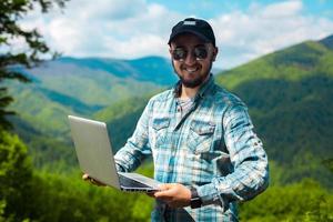 homme à lunettes de soleil et avec un ordinateur portable dans les mains photo