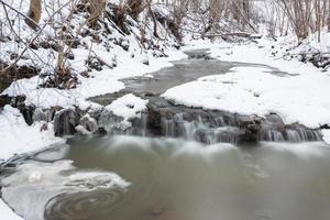 une petite rivière de forêt rocheuse en hiver photo