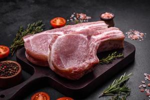 viande de porc crue fraîche sur les côtes avec des épices et des herbes sur une planche à découper en bois photo