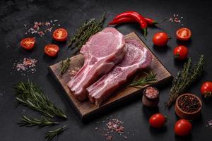 viande de porc crue fraîche sur les côtes avec des épices et des herbes sur une planche à découper en bois photo