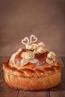 pain allongé sur la table avec des brindilles de bouleau en fleurs. gros plan de gâteau de mariage pain photo