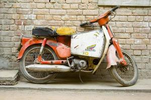 vieille moto garée par un mur de briques photo