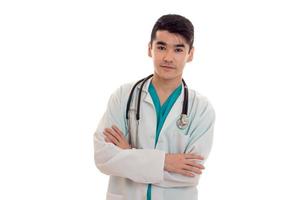 Attractive young brunette male doctor with stethoscope en uniforme regardant la caméra isolé sur fond blanc photo