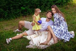 belle famille s'amusant au parc. parents avec fille se détendre à l'extérieur. photo