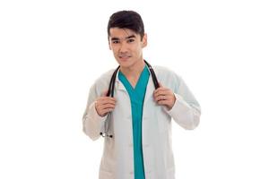 beau médecin élégant en uniforme bleu avec stéthoscope posant et regardant la caméra isolée sur fond blanc photo