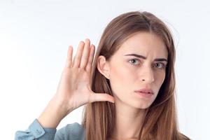 jeune fille attend avec impatience et tient sa main près de l'oreille en gros plan photo