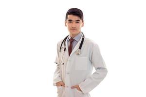 beau médecin élégant en uniforme avec stéthoscope posant et regardant la caméra isolée sur fond blanc photo