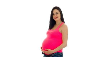 jolie fille enceinte aux cheveux noirs touchant son gros ventre et regardant la caméra isolée sur fond blanc photo