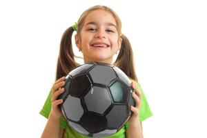 petite fille gaie en uniforme vert jouant avec un ballon de soccer photo