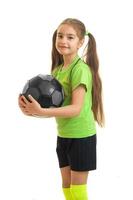 portrait vertical de mignonne petite fille en chemise verte tenant un ballon de football dans les mains photo