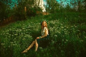 femme assise dans l'herbe avec une couronne sur la tête photo