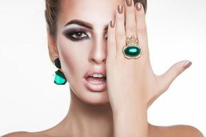 jolie jeune femme avec des diamants verts dans les accessoires en regardant la caméra photo