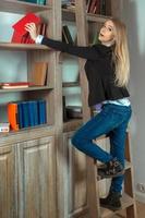 jolie fille blonde dans la bibliothèque à côté des livres photo