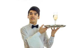 jeune serveur séduisant leva la tête et tenant un plateau avec des verres de champagne photo