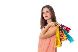 Une jeune fille sérieuse regarde au loin et garde les sacs à bandoulière isolés sur fond blanc photo