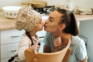 jolie petite fille homecook avec sa belle mère fait des crêpes dans la cuisine blanche. photo