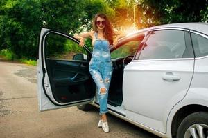 magnifique belle brune debout près d'une voiture blanche photo