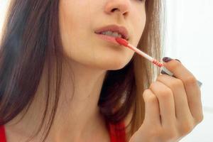 portrait d'une jeune fille qui peint ses lèvres rouge pailleté photo