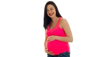 Jeune mère enceinte joyeuse rire isolé sur fond blanc en studio photo