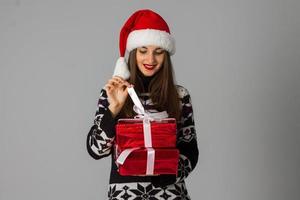 femme en pull chaud et bonnet de noel avec cadeau rouge photo