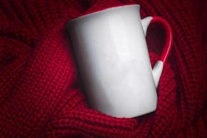 tasse blanche pour maquette posée sur un pull rouge confortable. photo