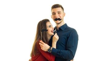 une jeune fille et un mec joyeux tiennent des moustaches noires en papier photo