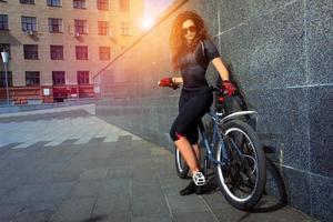 Belle jeune femme aux cheveux rouges bouclés à vélo photo