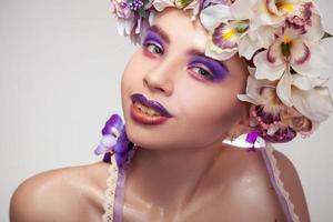 heureuse jeune fille avec une couronne sur la tête et un maquillage dans des tons violets photo