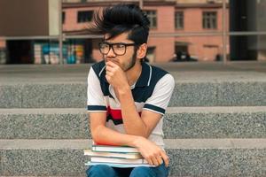 portrait de charmant jeune homme à lunettes et livres photo