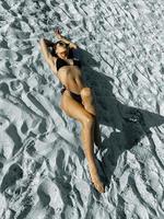 magnifique jeune femme prenant un bain de soleil sur le sable blanc photo