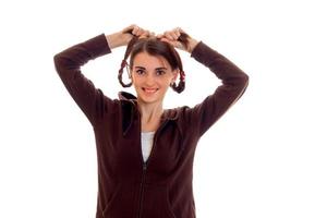 une joyeuse jeune fille en veste marron garde les mains des nattes photo