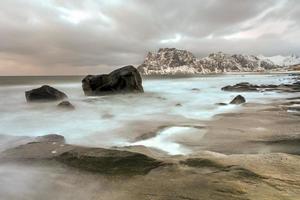 vagues qui coulent sur la plage d'utakleiv, îles lofoten, norvège en hiver.