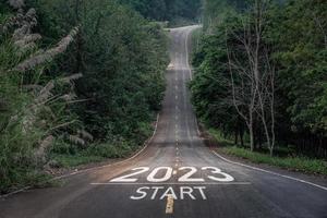 bonne année 2023, 2023 symbolise le début de la nouvelle année. la lettre commence le nouvel an 2023 sur la route dans la route de la nature a un concept d'écologie de l'environnement des arbres ou de papier peint de verdure. photo