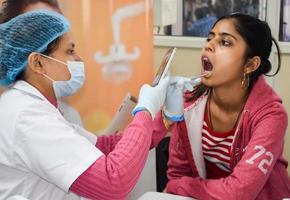 delhi, inde - 19 novembre 2022 - gros plan d'une femme dentiste faisant un examen dentaire de routine au patient, patient allongé sur une chaise lors du bilan de santé annuel, dentiste faisant un examen dentaire au patient photo