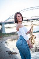 femme jouant du saxophone au coucher du soleil. photo