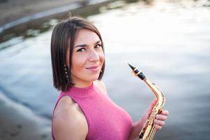 femme jouant du saxophone au coucher du soleil. photo