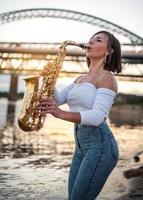 femme jouant du saxophone au coucher du soleil photo