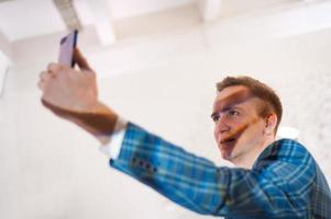 homme d'affaires élégant portant un costume bleu posant et prenant un selfie sur mobile photo