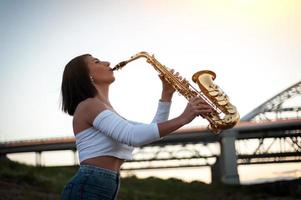femme jouant du saxophone au coucher du soleil photo