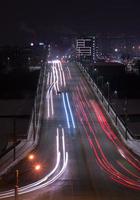 les sentiers lumineux de la voiture sur l'autoroute dans la ville moderne de nuit photo