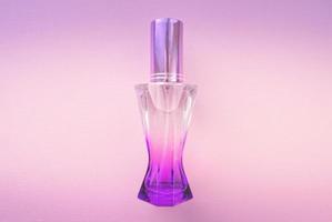 flacon de parfum sur fond rose. parfum féminin. flacon de parfum violet. photo