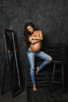 portrait de jeune femme enceinte portant des jeans avec de beaux cheveux longs photo