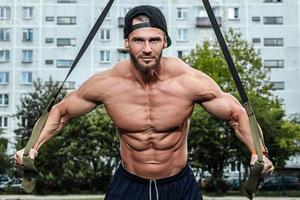 homme pendant l'entraînement avec des sangles de suspension dans la rue photo